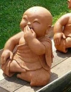 two small buddha statues sitting on top of a wooden bench