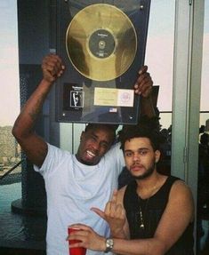 two men posing for the camera with their hands up in front of a record player