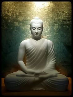 a white buddha statue sitting on top of a wooden table