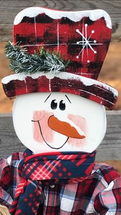 a wooden snowman with a red hat and plaid scarf on it's head