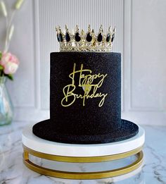 a black and gold birthday cake with a tiara on top that says happy birthday