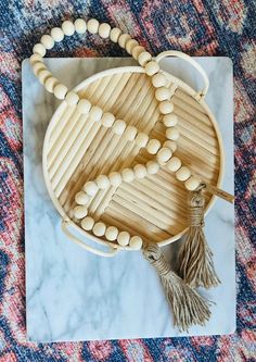 a wooden beaded purse sitting on top of a marble table next to a tassel