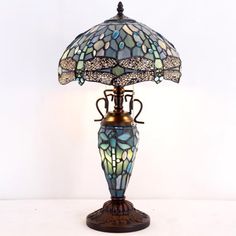 a lamp that is sitting on top of a white table with a blue and green glass shade