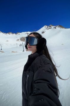 a woman wearing goggles standing in the snow