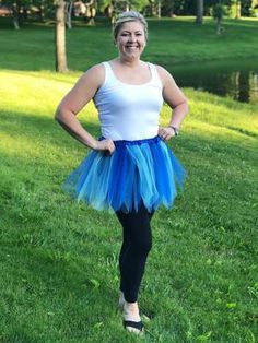 a woman standing in the grass wearing a blue and white tutu skirt with her hands on her hips