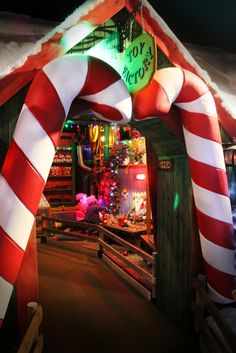 an archway decorated with candy canes and christmas lights at the entrance to a store