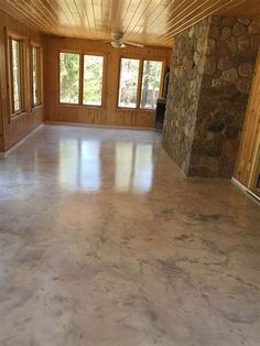 an empty room with wood paneling and stone fireplace