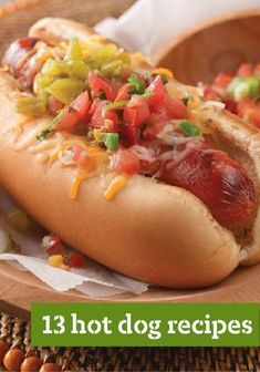 a hot dog with toppings sitting on top of a wooden plate next to a basket