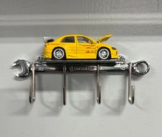 a yellow toy car is on top of a wrench holder with two keys attached to it