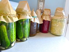 several jars filled with pickles sitting on top of a counter next to each other