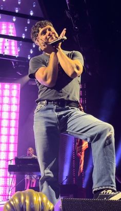 a man standing on top of a stage while holding a microphone in his right hand