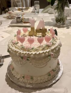 a white cake with pink flowers and candles