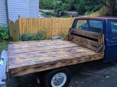 an old pickup truck is parked in front of a wooden fence