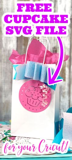 a paper bag with the words free cupcake svg file in pink and blue