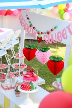 a table topped with lots of cakes and desserts covered in pink, green and red decorations