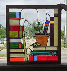 a stained glass window with a potted plant and books on the table next to it