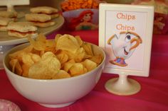 chips are in a bowl next to a sign and other food items on the table