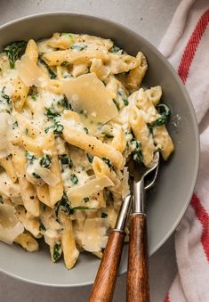 a bowl filled with pasta and spinach on top of a table