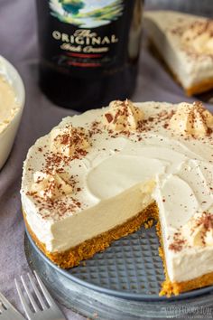 a cake with white frosting and cinnamon sprinkles sits on a plate next to a bottle of booze