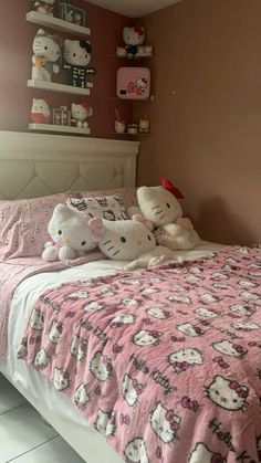 two hello kitty stuffed animals sitting on top of a pink and white bedspread