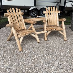 two wooden chairs sitting next to each other in front of a camper with the door open