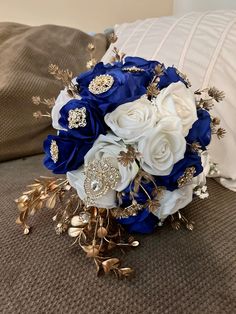 a bridal bouquet with blue and white flowers sits on a bed next to pillows