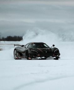 a black sports car driving through the snow