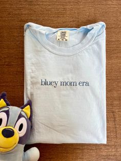 Bluey mom era with long dog on the sleeve!  This high quality comfort colors shirt is made to get softer with each wash and each shirt is embroidered by me. Shirts are made with love and care and made to order. Snag yours now for a unique fashion statement. Blue Cotton Tops With Custom Embroidery, Family Matching Cotton Tops With Custom Embroidery, Light Wash Cotton T-shirt, Blue Cotton Family Matching T-shirt, Vintage Embroidered Cotton T-shirt, Casual T-shirt With Custom Embroidery For Everyday, Casual Everyday T-shirt With Custom Embroidery, Light Blue Embroidered Cotton Tops, Everyday Cotton Tops With Embroidered Text