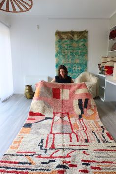 a woman sitting on top of a large rug in a living room next to a couch