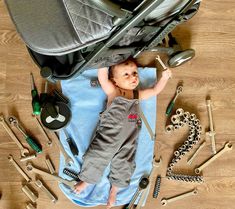 a baby laying on top of a blue blanket next to lots of tools