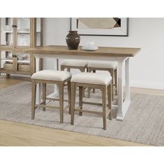 a dining room table with four stools and a vase on the end shelf next to it