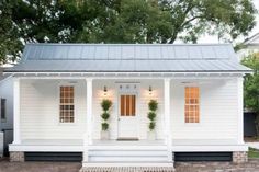 a white house with black trim and two windows on the front porch is featured in this article