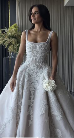 a woman in a white wedding dress standing next to a window