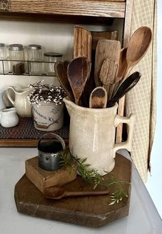 wooden spoons and other kitchen utensils in a white pitcher