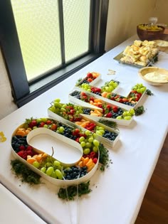 a table topped with lots of different types of fruits and veggies on trays