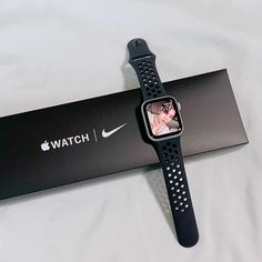 an apple watch sitting on top of a bed next to a black box with a photo