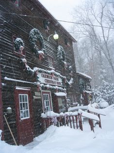 a snow covered building with christmas decorations on the front and side of it in winter