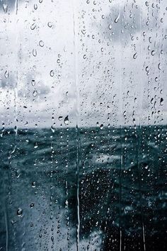 rain is pouring down on the window and water droplets are all over the glass,