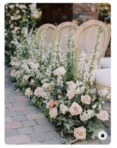 several chairs lined up with flowers and greenery