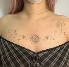 a woman with pink hair wearing a face mask and looking down at her chest tattoo