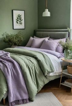 a bed with green and purple sheets in a room next to a table, chair and window