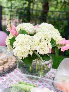 a vase filled with white and pink flowers on top of a table covered in food