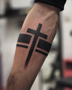 a man's arm with a black cross tattoo on the left side of his arm