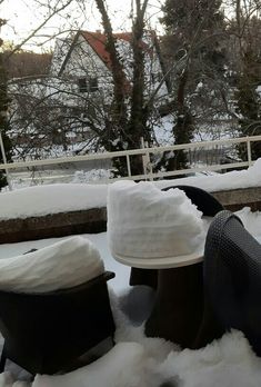 snow covered benches and foot stools in the middle of a snowy yard with houses in the background