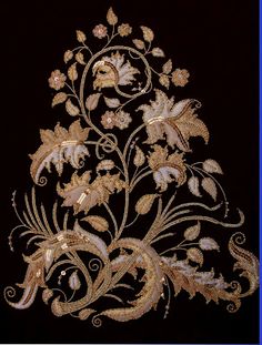 an embroidered design on a black background with gold and white flowers in the center, surrounded by vines and leaves