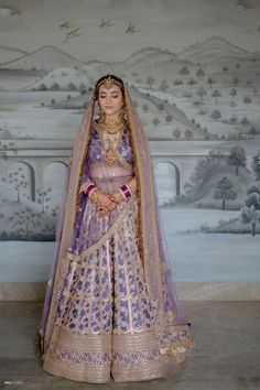 a woman in a purple and gold bridal gown standing next to a large painting