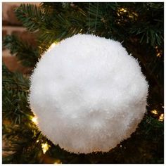 a white ball ornament hanging from a christmas tree