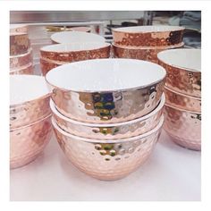 several bowls are stacked on top of each other in front of a counter with gold and white dishes