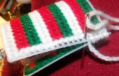 a pair of red and green knitted mitts sitting on top of a table