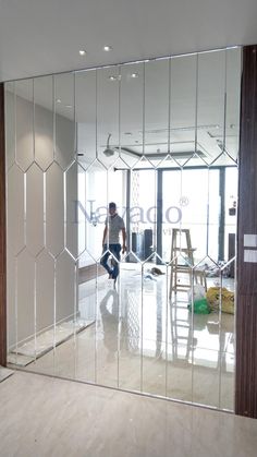 a man is standing in front of a large mirror with the reflection of him on it